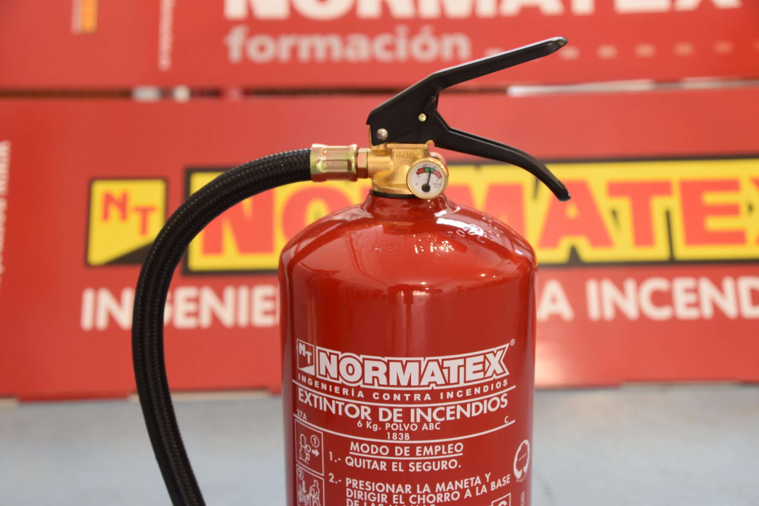 Un extintor Normatex con un fondo de cartel también Normatex, empresa de extintores Murcia