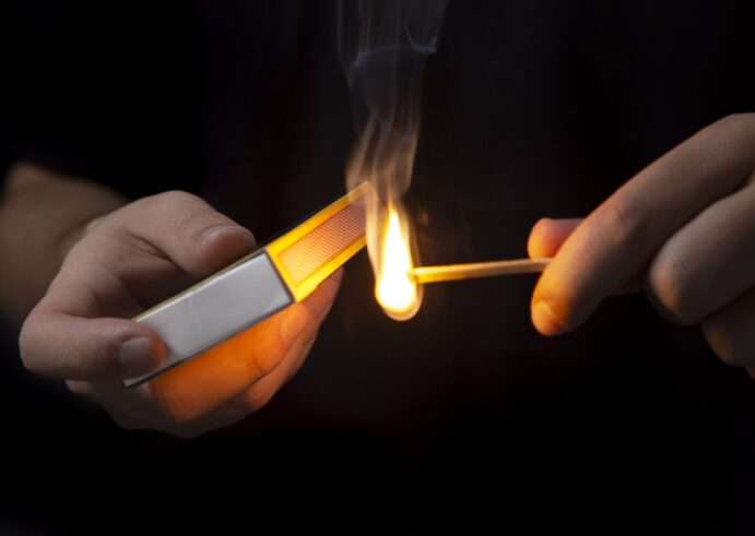 tipos de fuego, unas manos encendiendo una cerilla sobre fondo negro